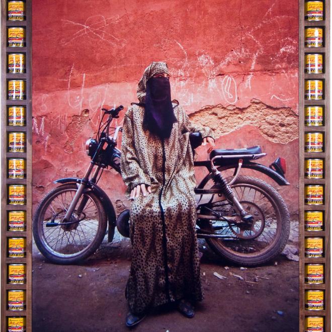 A photograph from Hassan Hajjaj's exhibition, The Path, featuring a woman wearing a cheetah print burqa with a motorbike in the background.