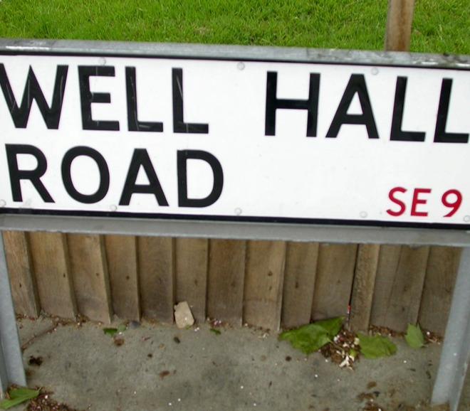 A photograph of a street sign which reads "Well Hall Road"