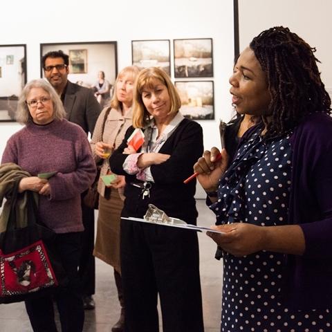 A photograph of a woman taking a group of people on a gallery tour at the New Art Exchange